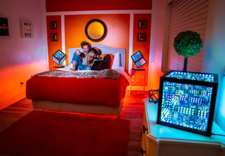 Pareja en cama iluminada por luces LED. Cada color de las luces LED tiene un propósito: rojo para pasión, azul para calma, verde para energía.