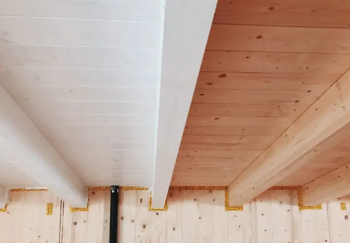 Soffitto con perline in legno sbiancato e travi a vista in legno naturale.