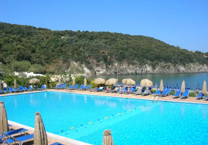 Piscina con lettini e ombrelloni, vista mare e collina verde. Informazioni su Negombo prezzi e orari per una vacanza rilassante.