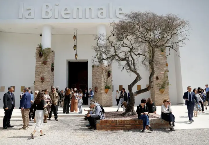 Ludzie spacerują przed budynkiem z napisem "la Biennale". Atmosfera jak na Biennale Wenecja 2026.