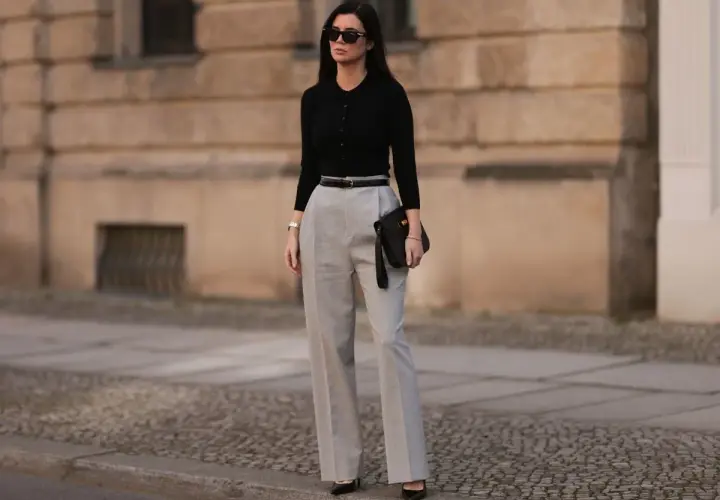 Eleganckie stylizacje na urodziny: czarna bluzka, szare spodnie z wysokim stanem, pasek i kopertówka. Idealny zestaw na świętowanie!