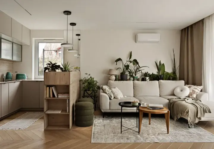 Przytulny szary salon z dużą ilością zielonych roślin, jasną kanapą i drewnianymi meblami.