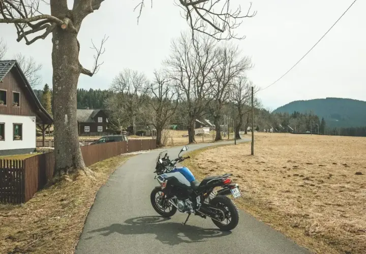 Motocykl na drodze w Czechach, wśród domków i drzew.