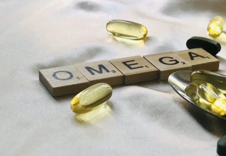 Capsule di olio di pesce e tessere con la scritta OMEGA. Chissà dopo quanto tempo fanno effetto gli omega-3 per il benessere.