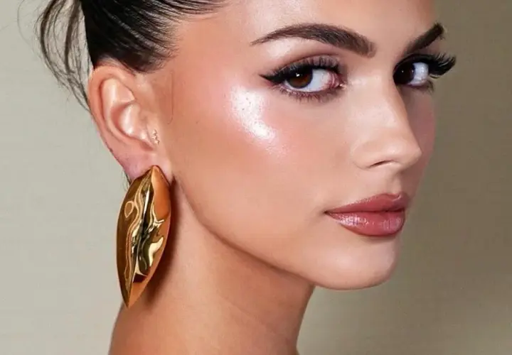 Rostro con maquillaje radiante, destacando el uso de iluminador en barra para un brillo natural.