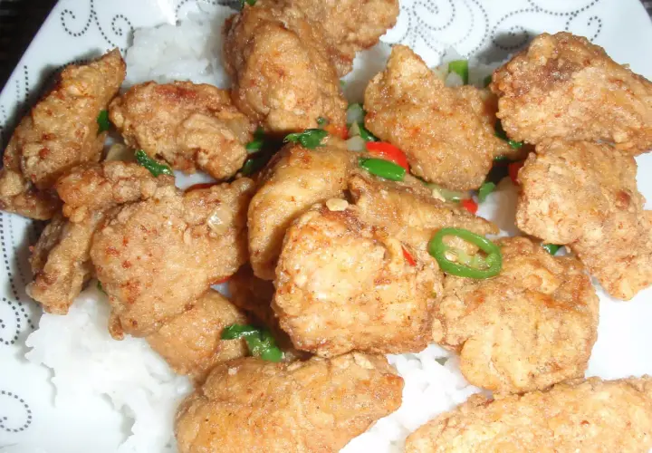 Chrupiący kurczak po koreańsku yangnyeom z podwójnie smażoną panierką ze skrobi, podany na ryżu z papryczkami chili.