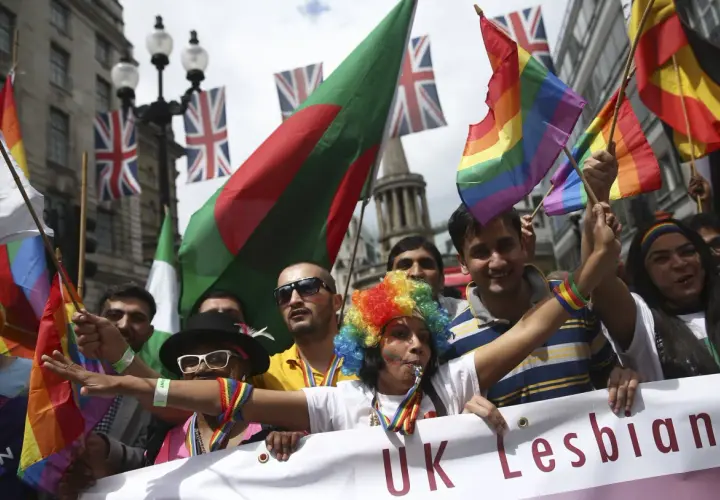 People wave rainbow and national flags at a pride parade, showing why understanding diversity is important for unity and celebration.