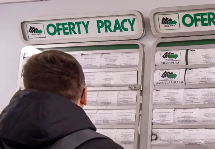 Mężczyzna przegląda ogłoszenia o pracę w urzędzie pracy. Szuka zatrudnienia, być może licząc na zasilek dla bezrobotnych.