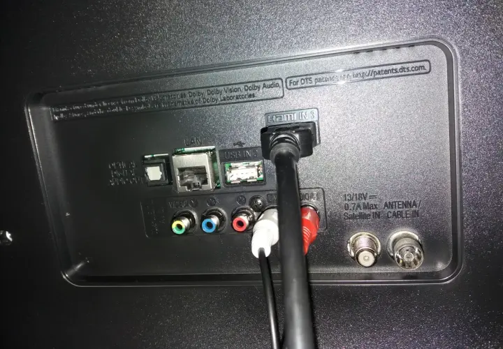 Tył telewizora z podłączonymi kablami HDMI, USB, LAN i audio.