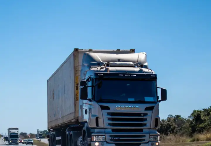 Ciężarówka Scania z kontenerem na autostradzie pod błękitnym niebem.