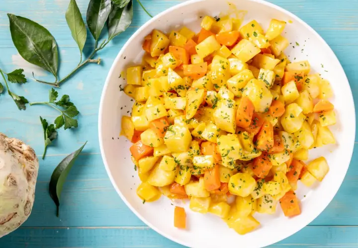 Insalata di sedano rapa e carote a cubetti, condita con erbe aromatiche. Un'idea fresca per le tue ricette crudiste.