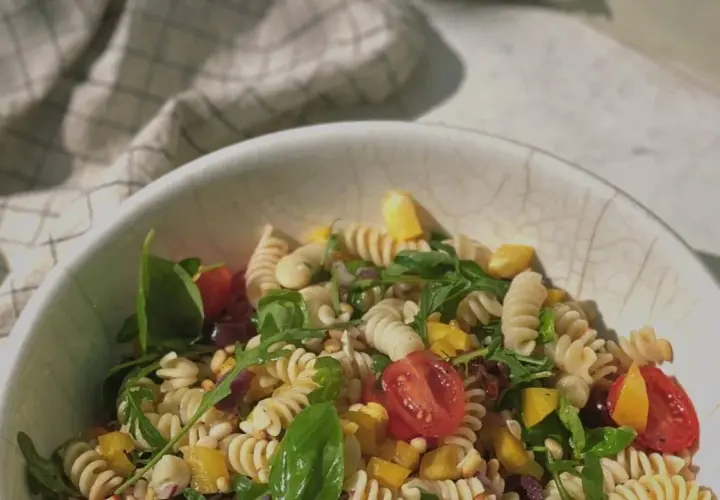 Leckerer Weight Watchers mediterraner Pastasalat mit Fusilli, Kirschtomaten, Rucola und gelber Paprika in einer Schüssel.