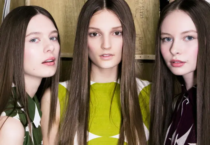 Trzy modelki z długimi włosami, prosto obciętymi, prezentują nowy trend fryzur.