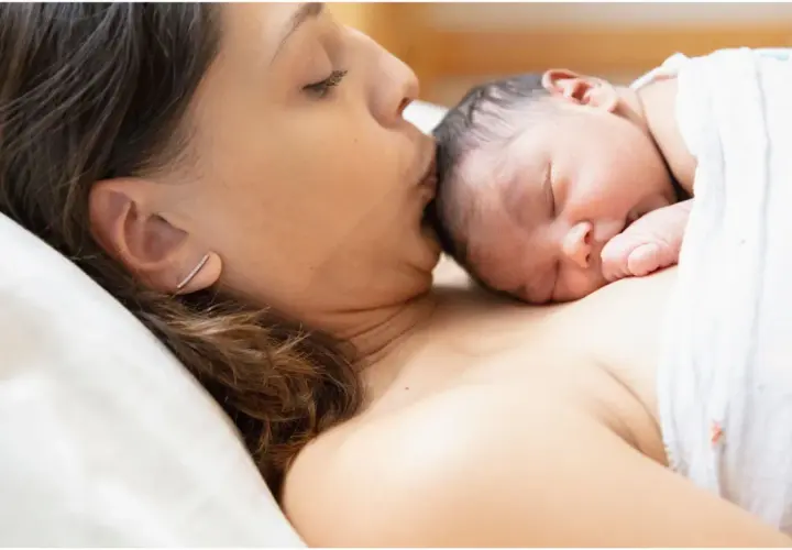Mamma bacia il suo neonato, un momento di tenerezza che celebra la fine delle 38 settimane di gravidanza, quanti mesi sono circa nove.
