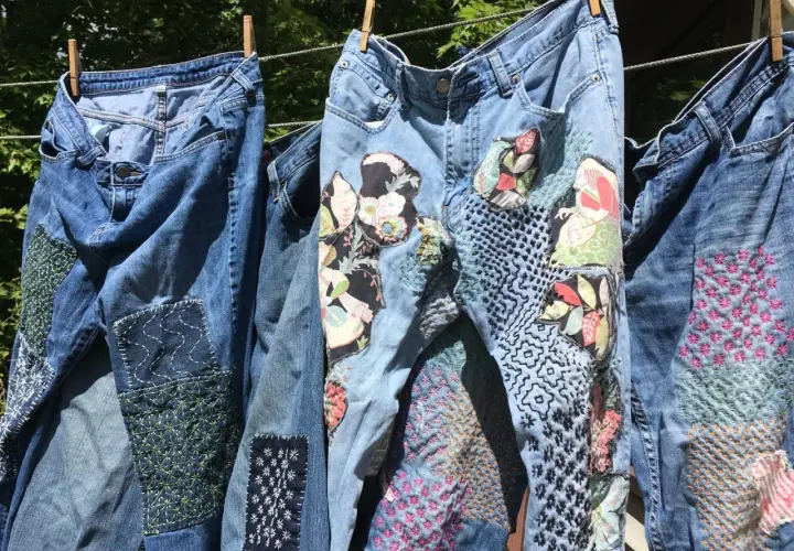 Jeans repaired with colorful patches and intricate stitching, showcasing creative ways how to darn.