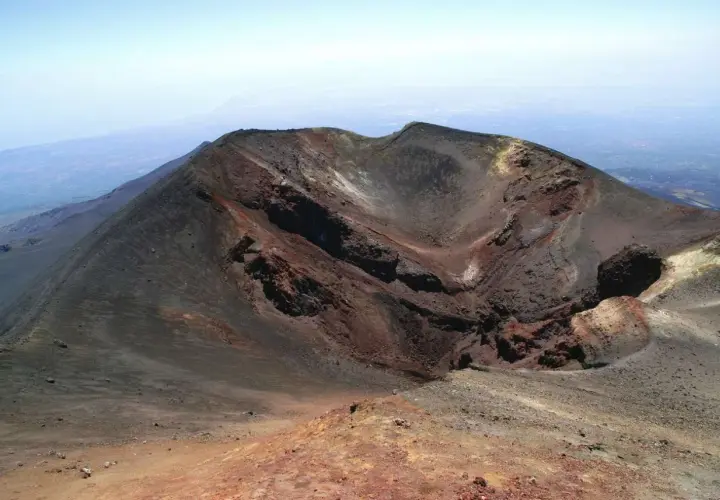 Crateri dell'Etna, un paesaggio lunare da esplorare con la propria auto. Rocce vulcaniche rosse e nere sotto un cielo azzurro.