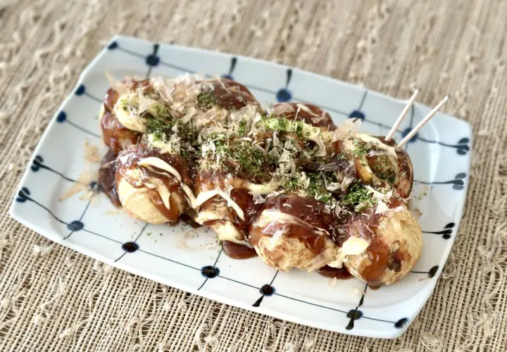 A plate of takoyaki, drizzled with sauce and mayonnaise, topped with bonito flakes and nori. Perfect for a homemade takoyaki sauce recipe.