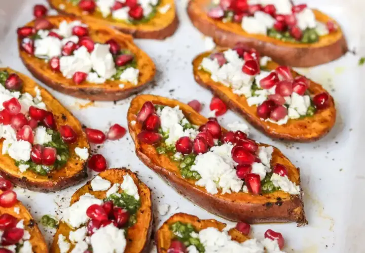 Pieczone bataty z piekarnika, udekorowane zielonym pesto, fetą i pestkami granatu. Pyszna przekąska!