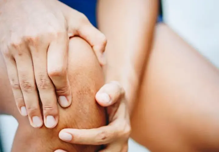 Hände umfassen ein Knie, das auf Schmerzen im Bereich des pes anserinus superficialis und profundus hindeutet.