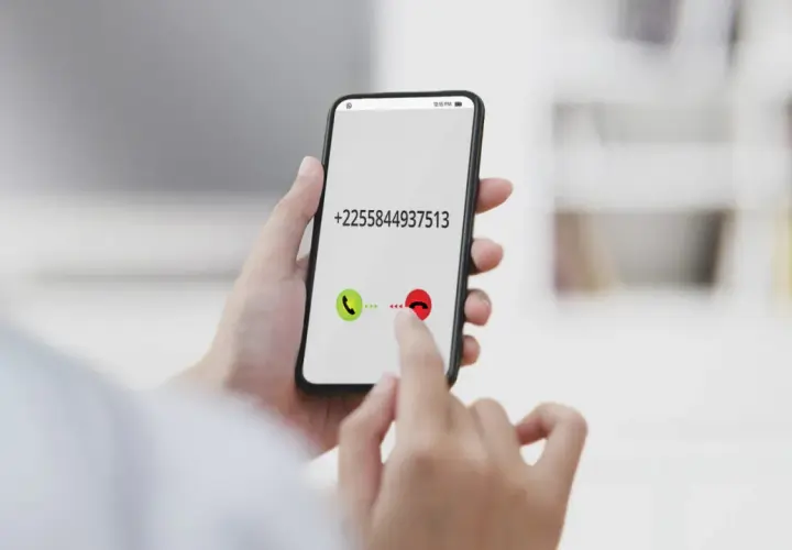 Dłoń trzyma smartfon z numerem +2255844937513. Palec wskazuje przycisk odbierania połączenia, jakby wybierał kierunkowy 40.