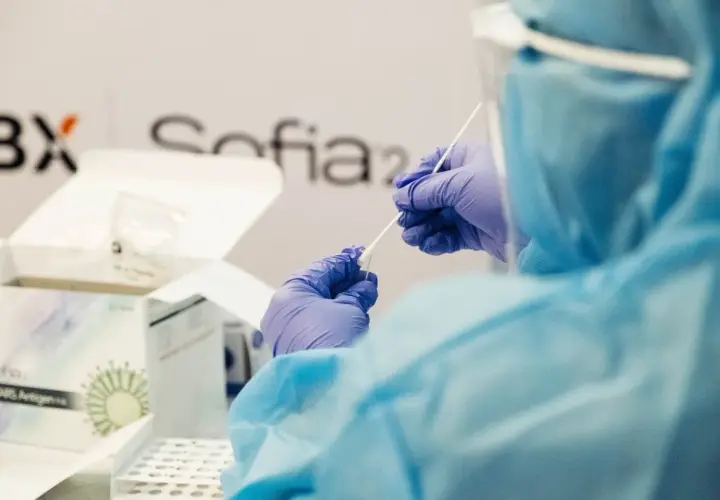 Osoba w kombinezonie i rękawiczkach przygotowuje testy Sofia SARS Antigen. To ważny kurs, który pomaga w diagnostyce.