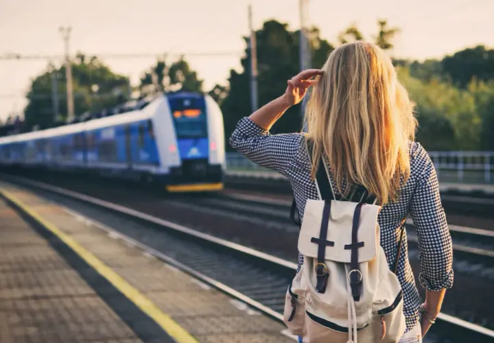 Dziewczyna z plecakiem czeka na pociąg, który zabierze ją do miast nad morzem.