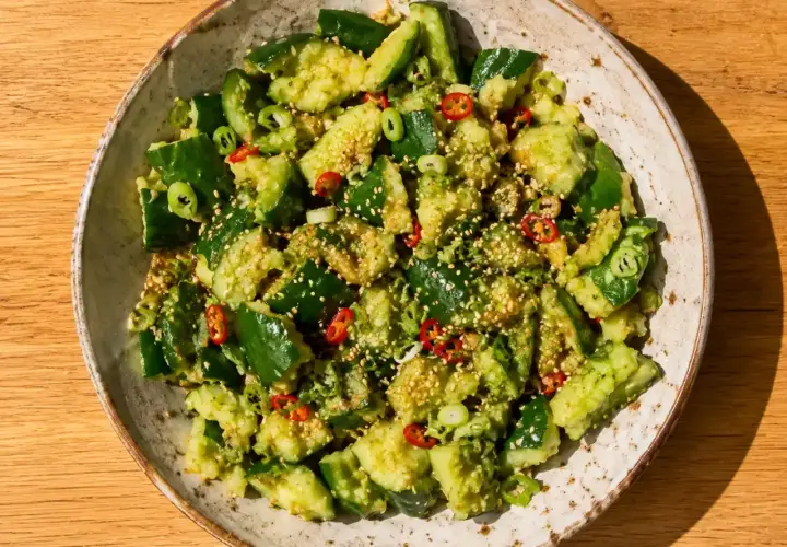 En skål med asiatisk gurksallad, toppad med sesamfrön, chili och salladslök. En fräsch och smakrik rätt.