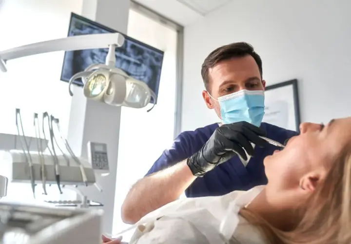 Dentista esamina un paziente, con un occhio attento alla salute orale. Un sorriso sano vale più di un bonus dentista 500 euro.