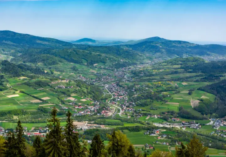 Widok na dolinę z zabudowaniami i polami uprawnymi w Beskidzie Wyspowym.