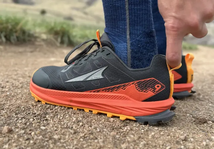 Close-up of a black Altra Lone Peak 9 trail running shoe with orange accents, ready for adventure.