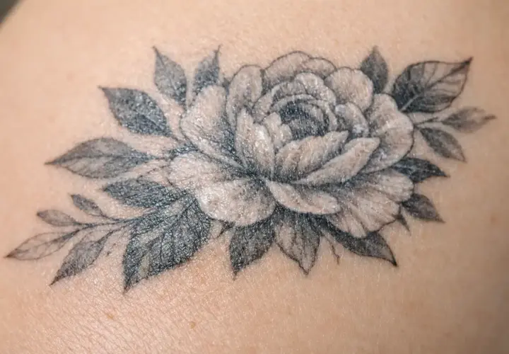 Un magnifique tatouage de pivoine et de feuilles, délicatement dessiné sur la peau.