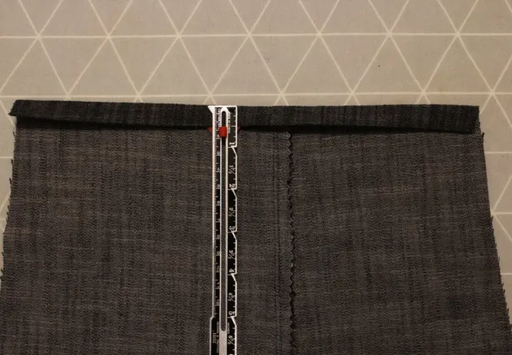 A ruler measures a dark grey cotton twill fabric. The fabric has a visible weave, characteristic of what is cotton twill.