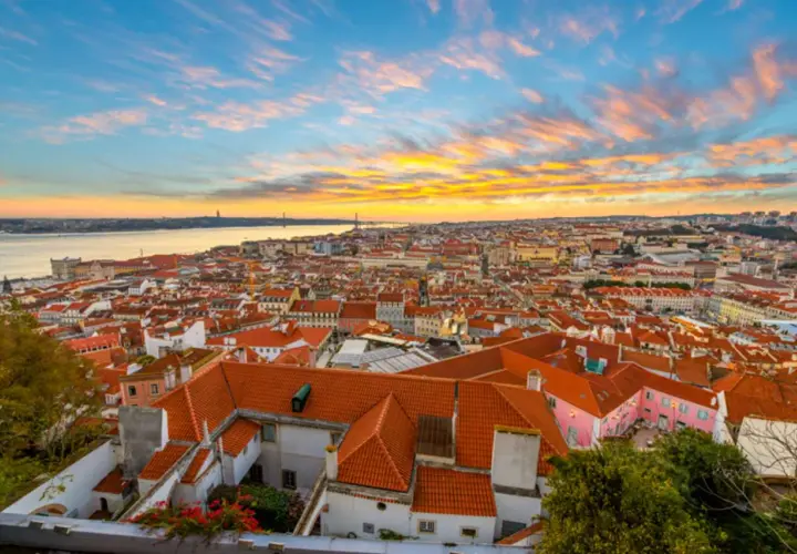 Un espectacular atardecer lisboa baña con tonos dorados y rosados el cielo sobre la ciudad y el río Tajo.