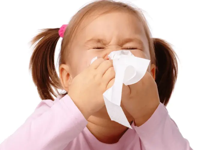 Bambina con raffreddore estivo, usa un fazzoletto per soffiarsi il naso.