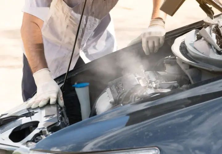 Para wylatuje z gorącego silnika po jeździe. Mechanik w rękawiczkach sprawdza auto.