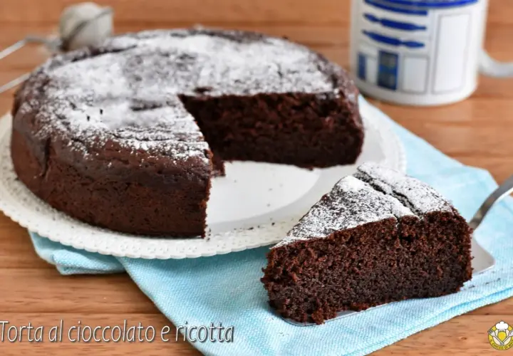 Torta al cioccolato e ricotta, soffice e golosa, spolverata di zucchero a velo. Una fetta invitante attende di essere gustata.