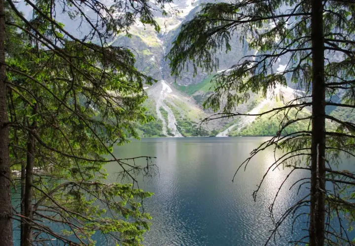 Widok na Morskie Oko, gdzie góry odbijają się w tafli wody. To miejsce, gdzie rodzi się legenda o morskim oku.