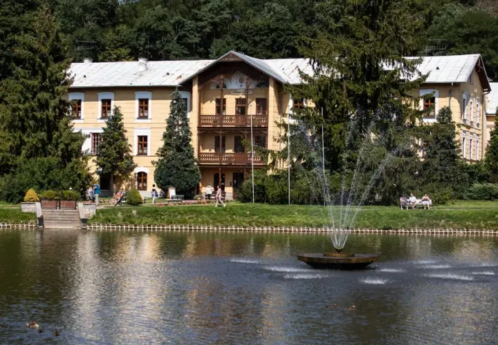 Piękny budynek sanatorium godne polecenia, z fontanną i stawem, otoczony zielenią.