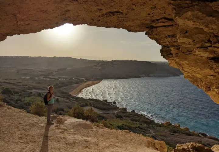Frauenblick auf die Bucht von Malta im Dezember. Das Wetter ist mild, die Sonne scheint, und die Wellen brechen am Strand.