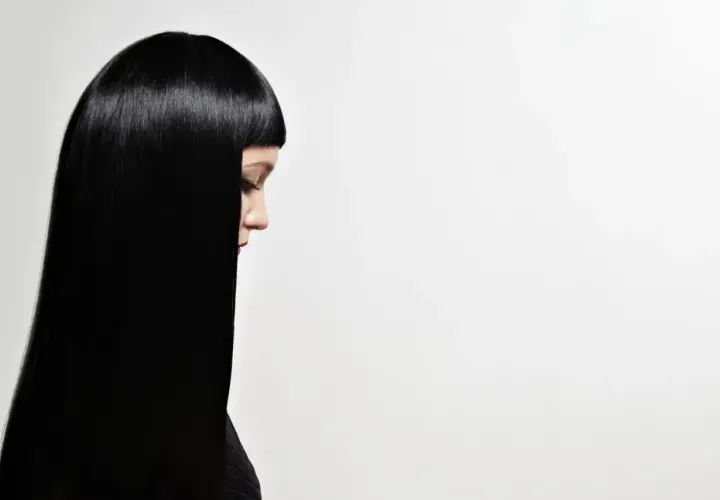 Perfil de mujer con cabello liso y brillante, negro azabache, cayendo sobre su hombro.