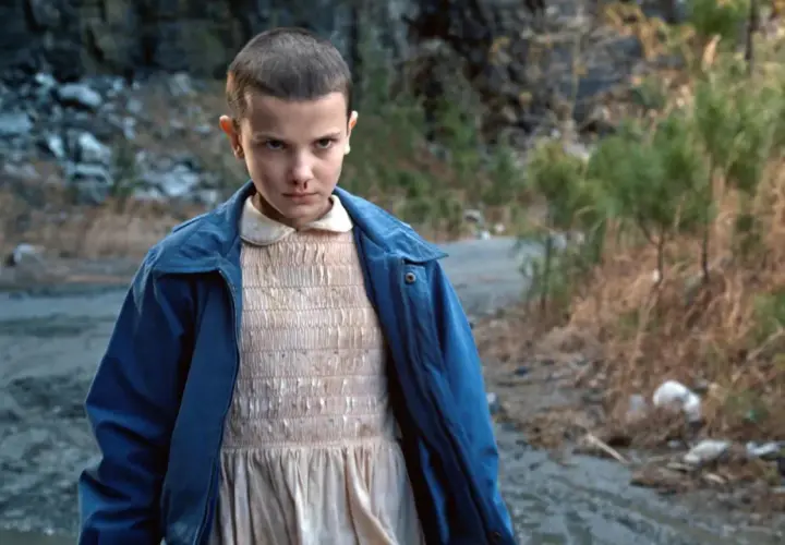 Nastka z Stranger Things, z nosem krwawiącym, stoi na brudnej drodze.