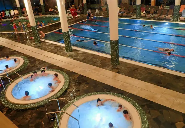 Widok na baseny termalne z jacuzzi i pływającymi ludźmi.