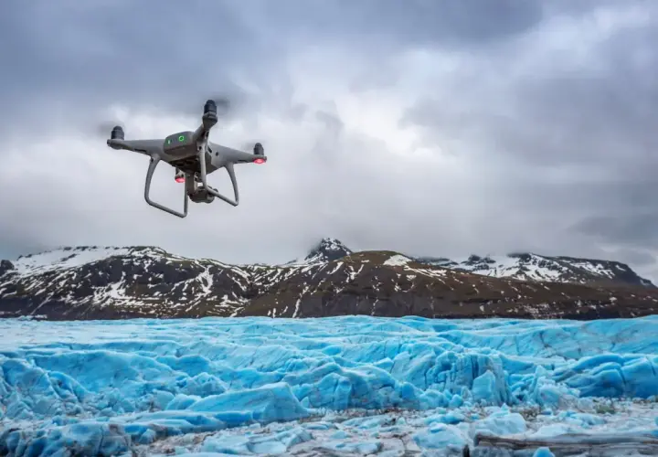 Dron rejestruje spektakularne zdjęcia lodowca o intensywnie niebieskiej barwie, z ośnieżonymi górami w tle.
