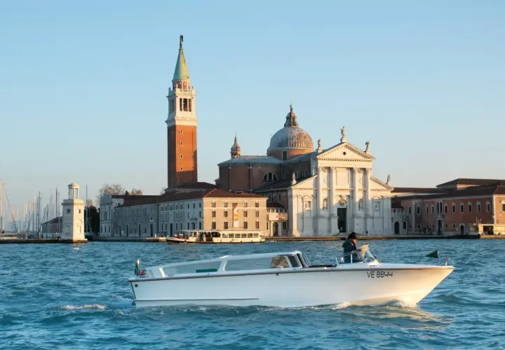 Taxi boat naviguant sur le Grand Canal, avec l'église San Giorgio Maggiore en arrière-plan. Idéal pour connaître le tarif taxi Venise.