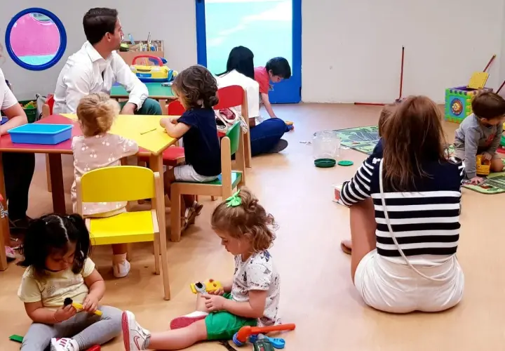 Niños jugando y un adulto observando, parte de lo que es el periodo de adaptación en un aula.
