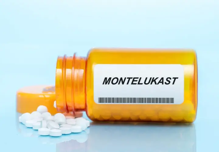 Pigułki leku Montelukast wysypują się z pomarańczowej buteleczki.