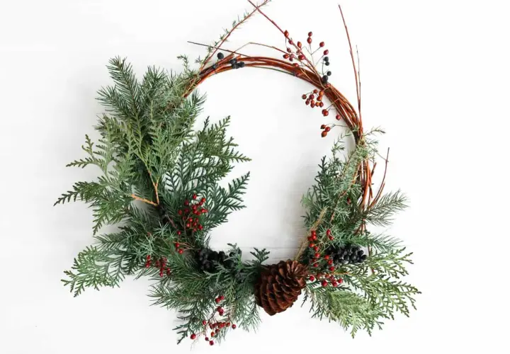 Ghirlanda rustica con pigne, bacche rosse e rami. Un'idea per imparare come fare una ghirlanda fai da te.