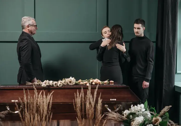 Smutek i żałoba. Rodzina w czerni przy trumnie. Jak się ubrać na pogrzeb? Elegancko i z szacunkiem.