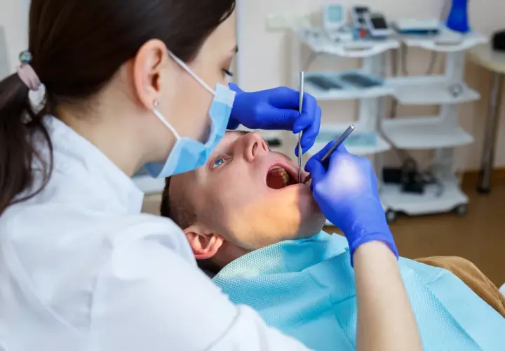 Dentystka bada zęby pacjenta. Zastanawiasz się, na ile dentysta może wystawić L4? Zależy to od stanu zdrowia pacjenta i zaleceń lekarskich.