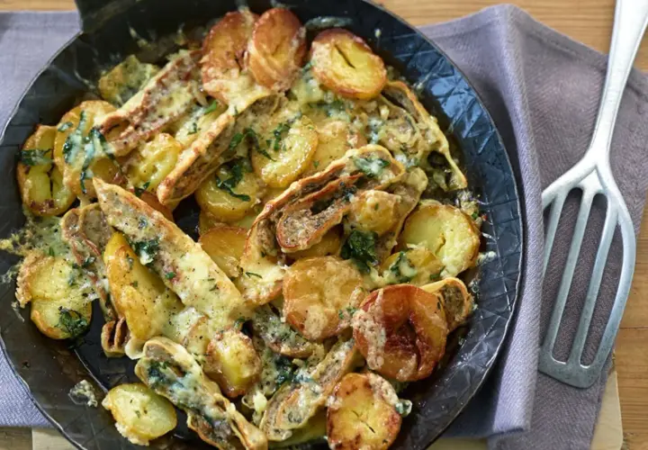 Herzhafte Maultaschen-Pfanne mit goldbraunen Kartoffelscheiben und geschmolzenem Käse, garniert mit frischen Kräutern.